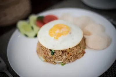 a plate of food with an egg on top of rice at The Tukad Villa in Seminyak
