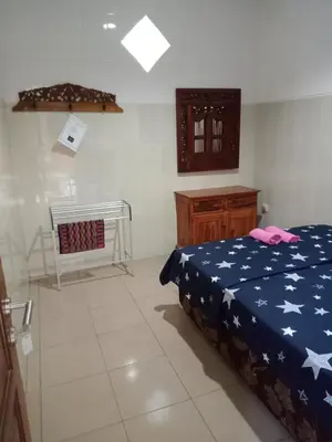 a bedroom with a bed and a dresser in it at Cempaka 2 Homestay in Legian