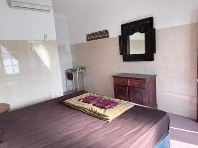 a bedroom with a bed and a vanity and a mirror at Cempaka 2 Homestay in Legian