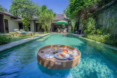 a swimming pool with a table in the middle at Chimera Villas in Seminyak