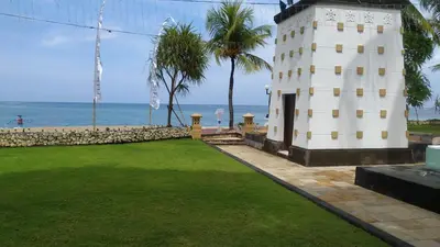 a white lighthouse next to the ocean with palm trees at The Patra Bali Resort & Villas - CHSE Certified in Kuta