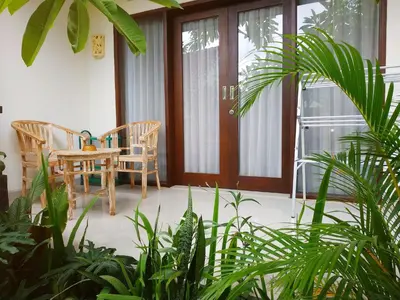 a porch with a table and chairs and plants at Dwiputra Guest House in Canggu