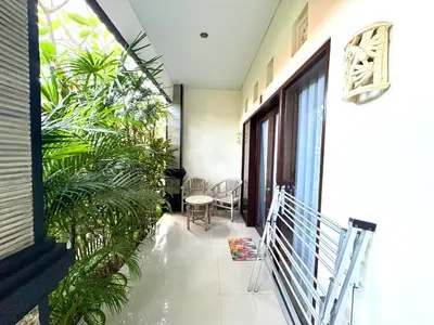 a balcony of a house with plants and a table at Dwiputra Guest House in Canggu