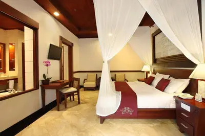 a hotel room with a bed and a desk and a bed istg at Bali Tropic Resort & Spa - CHSE Certified in Nusa Dua