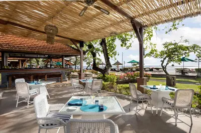 a patio with tables and chairs and a bar at Bali Tropic Resort & Spa - CHSE Certified in Nusa Dua