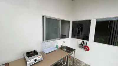 a kitchen with a counter with a sink and two windows at Kampoeng Saya in Seminyak
