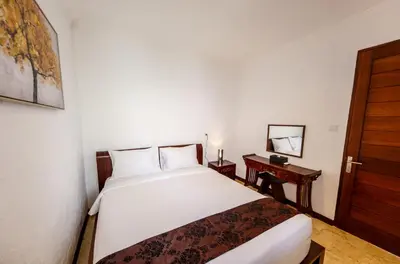 a bedroom with a white bed and a wooden door at Villa Suzuki 1 Seminyak in Seminyak