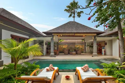 a villa with a swimming pool and two lounge chairs at The Buah Bali Villas in Seminyak