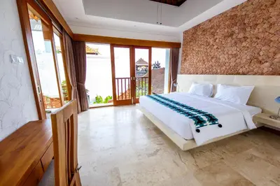 a bedroom with a large white bed and a balcony at Villa Suzuki 2 Seminyak in Seminyak