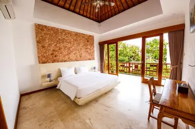 a bedroom with a bed and a desk and windows at Villa Suzuki 2 Seminyak in Seminyak