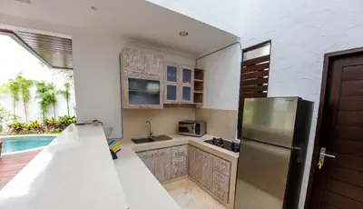 a kitchen with a stainless steel refrigerator and a pool at Villa Suzuki 3 Seminyak in Seminyak