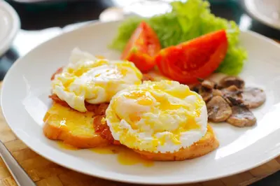 a plate with two fried eggs on top of food at Heliconia Villa in Seminyak