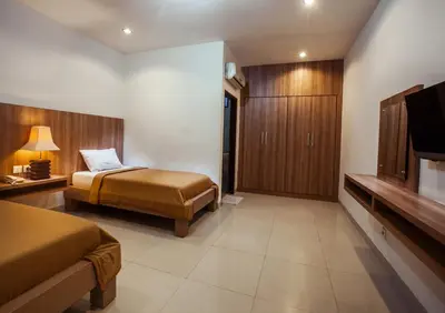 a hotel room with two beds and a flat screen tv at Simpang Inn Hotel in Legian