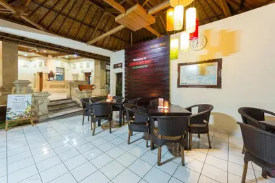 a restaurant with tables and chairs and a clock on the wall at Simpang Inn Hotel in Legian