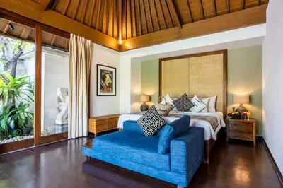 a bedroom with a bed and a blue couch at The Akasha Seminyak Bali Luxury Villas in Seminyak