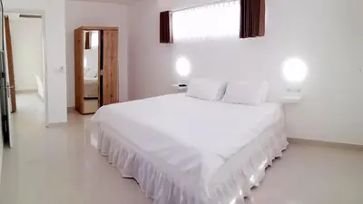 a white bedroom with a large white bed and a window at The Bali Bubble in Sanur