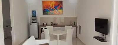 a kitchen with white chairs and a table and a tv at The Bali Bubble in Sanur