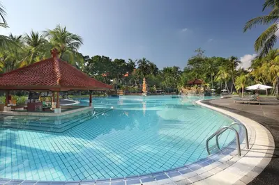 a large swimming pool at a resort with palm trees at Bintang Bali Resort in Kuta