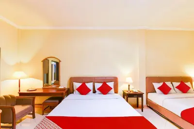 a hotel room with two beds with red pillows at Super OYO Townhouse Oak Maxi Hotel Legian in Kuta