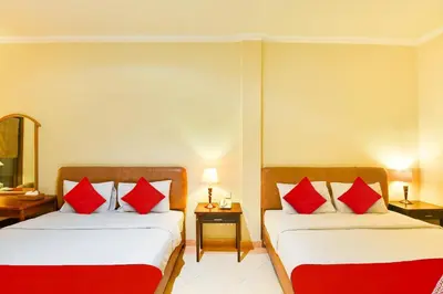 two beds in a hotel room with red pillows at Super OYO Townhouse Oak Maxi Hotel Legian in Kuta