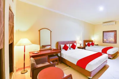 a hotel room with two beds and a desk at Super OYO Townhouse Oak Maxi Hotel Legian in Kuta