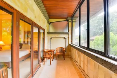 a room with a bed and a table and windows at Super OYO Townhouse Oak Maxi Hotel Legian in Kuta