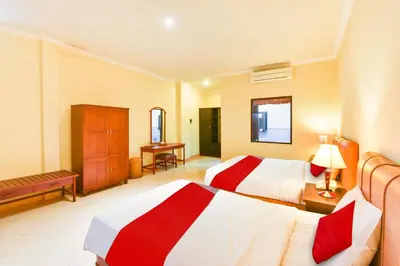 a hotel room with two beds and a desk at Super OYO Townhouse Oak Maxi Hotel Legian in Kuta
