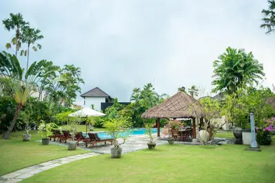 a resort yard with a pool and tables and chairs at Sienna Villas Seminyak in Seminyak