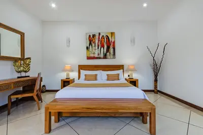 a bedroom with a bed and two tables and a desk at Villa Mienna in Seminyak