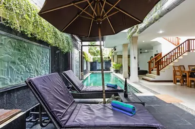 a swimming pool with two lounge chairs and an umbrella at Villa Mienna in Seminyak