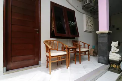 a porch with two chairs and a wooden door at Anantaya Home Denpasar in Denpasar