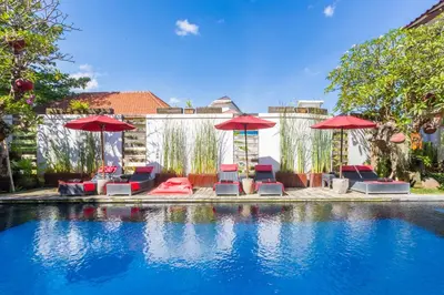 a swimming pool with red umbrellas and chairs at Kamar Kamar Boutique Hotel in Seminyak