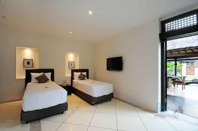 a bedroom with two beds and a tv in it at Villa Seminyak William in Seminyak