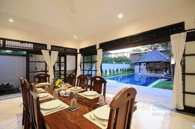 a dining room with a table and chairs and a pool at Villa Seminyak William in Seminyak