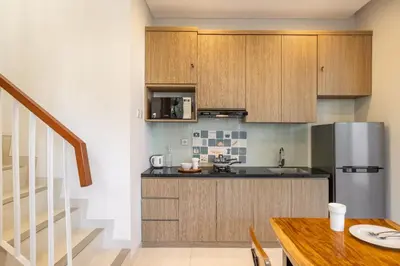 a kitchen with wooden cabinets and a wooden table at Cove Villa Prana in Jimbaran