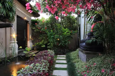 a garden with pink flowers and a walkway at Villa Maju in Seminyak