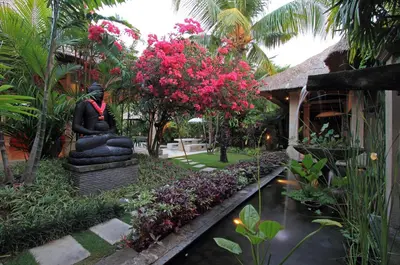 a statue sitting next to a pond in a garden at Villa Maju in Seminyak