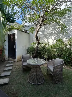 a table and two chairs and a table and a tree at Artemis Villa Hotel in Seminyak
