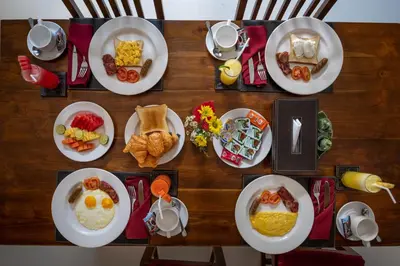 a wooden table with plates of breakfast food on it at Gracia Bali Villas & Apartment Managed by Manara in Seminyak