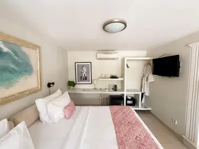 a bedroom with a white bed and a desk at Casa Artista By Kresna Hospitality in Seminyak