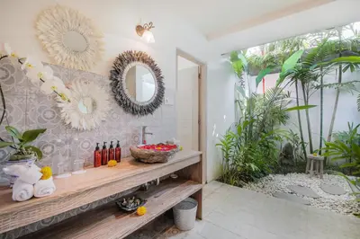 a bathroom with a wooden bench and mirrors on the wall at Villa Maviba in Seminyak