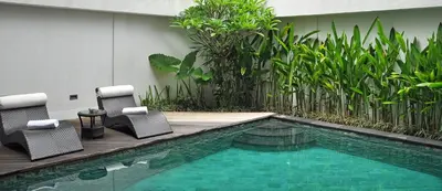 a swimming pool with two chairs and a wooden deck at Villa La Sirena by Nagisa Bali in Seminyak