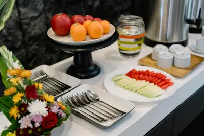 a buffet with plates of fruits and vegetables on a table at Everyday Hotel Kuta Central in Kuta