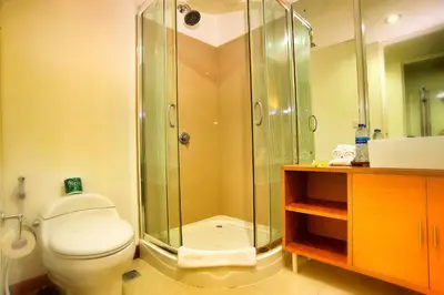 a bathroom with a toilet and a glass shower at Sunset Residence and Condotel in Legian