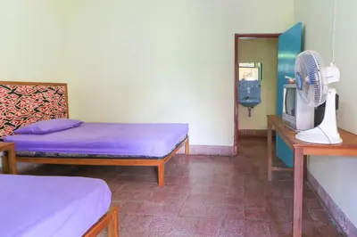 a room with two beds and a tv and a fan at Mertha Jati Hotel in Kuta