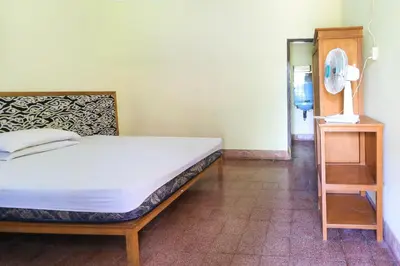 a bedroom with a bed and a table and a fan at Mertha Jati Hotel in Kuta