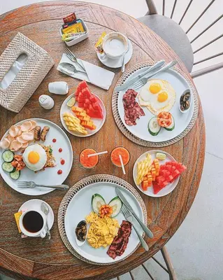 a wooden table with plates of breakfast food on it at Casamaya Villa in Legian