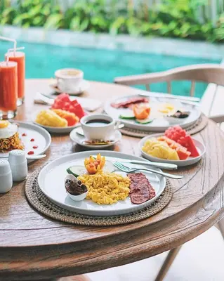 a table with plates of breakfast food on it at Casamaya Villa in Legian