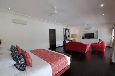a bedroom with a bed and a living room with red chairs at Villa Eva in Seminyak