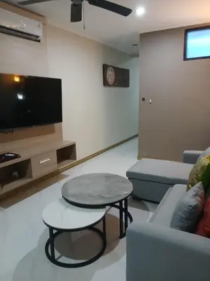 a living room with a table and a couch and a tv at Kuta Regency B10 One Bedroom Villa in Kuta